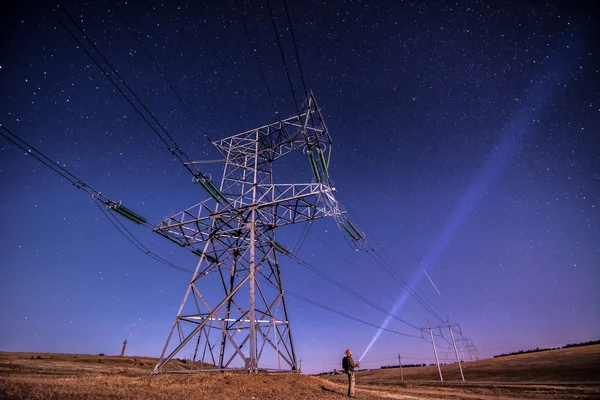 Electricity power poles on alone man -  night sky and stars