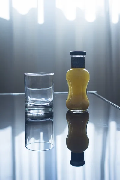 Bottle of orange juice and empty glass on table
