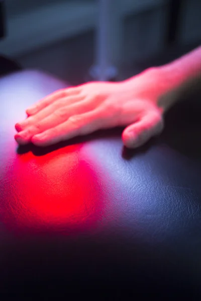 Patient hand in red physiotherapy heat treatment