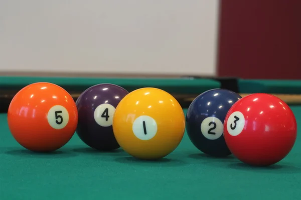 Yellow snooker ball with number one on it with other colorful balls placed in a row on a table - snooker game concept image