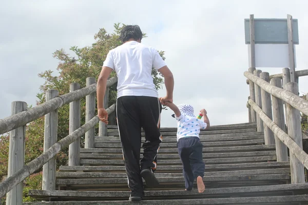 Young father and son holding hands & walking up wooden steps. family time concept with youthful father talking his son up the stairs
