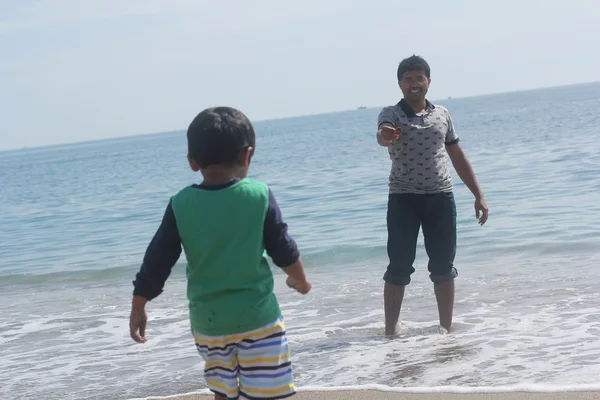 Indian father and son playing in the calm ocean sea water waves