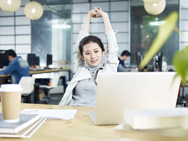 Young asian business woman stretching in office