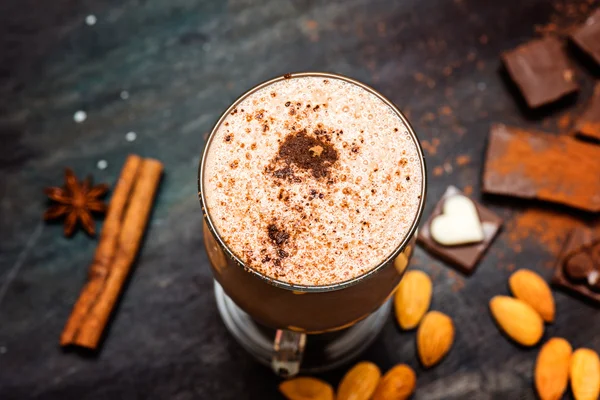 Coffee chocolate smoothie on a dark background with chocolate and nuts.