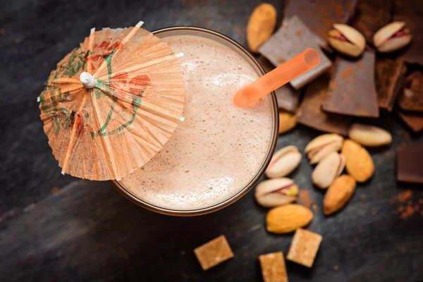 Coffee chocolate smoothie on a dark background with chocolate and nuts.