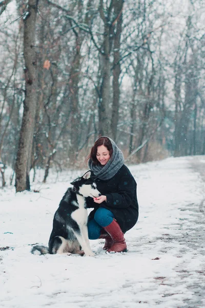 Young woman with husky dog in the winter park