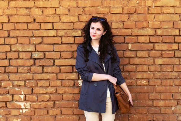 Brunette woman near bricks wall