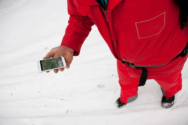 Phone and map in the hands of men hiking winter forest