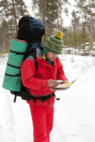 Man with phone and map in hands traveling winter forest