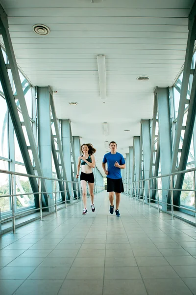 Man and woman running in the modern bridge construction