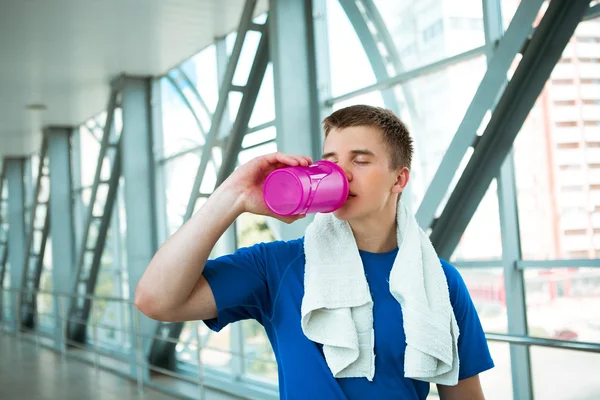 Man holding bottle of water, taking a break from exercise.