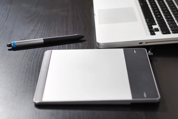 Graphic tablet on the table with notebook.