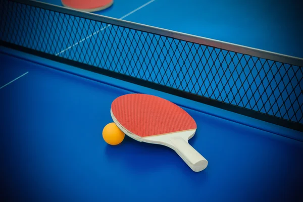 Pingpong rackets and ball highlighted on a blue pingpong table