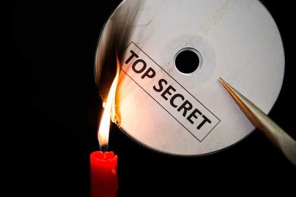 Burning a top secret compact disc with candle in dark