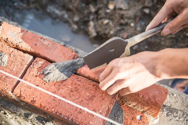 Plasterer making up a brick wall with cement