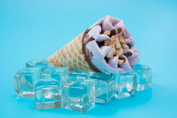 Peanut flavor ice cream cone on top of ice cubes on blue background