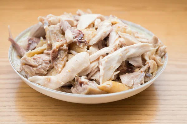 Dish of shredded boiled chicken on wood table