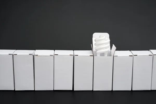 Line of boxes with one open, an energy saving light bulb stands out