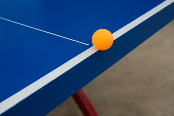 Pingpong ball hits the edge of a blue pingpong table