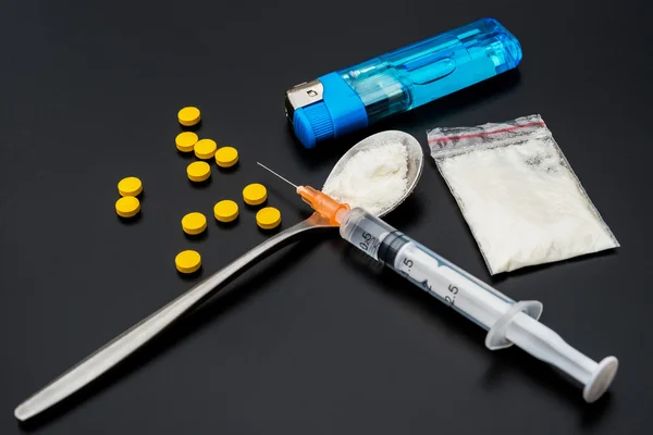 Disposable syringe and pack of white powder and pills and lighte