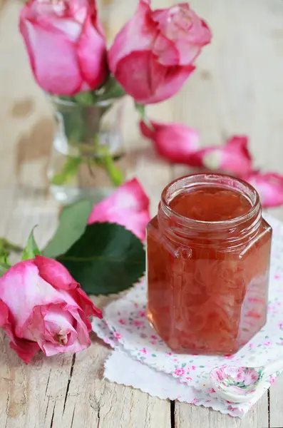 Jar of rose petal jam on a wooden table with flowers roses, sele