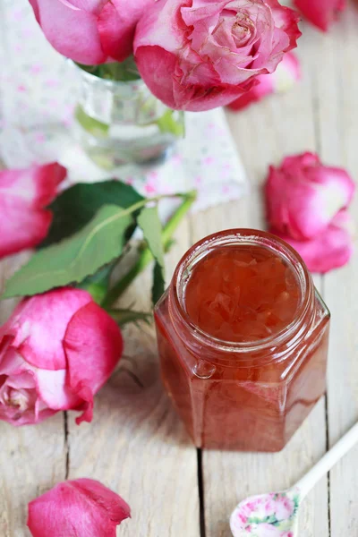 Jar of rose petal jam on a wooden table with flowers roses, sele