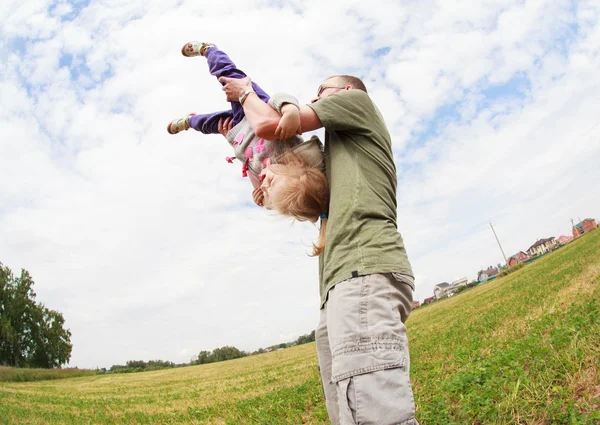 Dad playing with his happy little daughter, holding her upside d