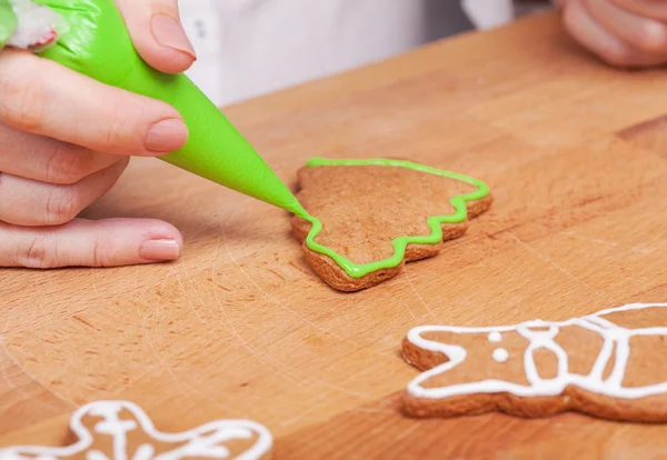 Decorating gingerbread cookies (Christmas tree) with green icing