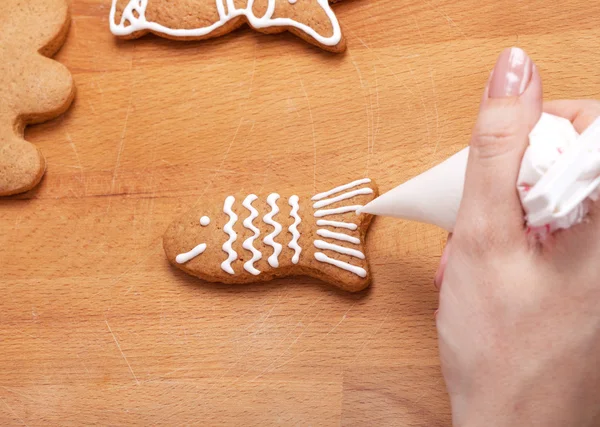 Decorating gingerbread cookies (fish) with white icing, selectiv