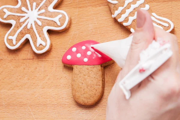 Decorating gingerbread cookies (mushroom) with red and white ici