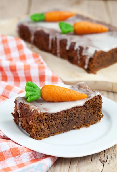 A piece of carrot cake with nuts, decorated with marzipan carrot