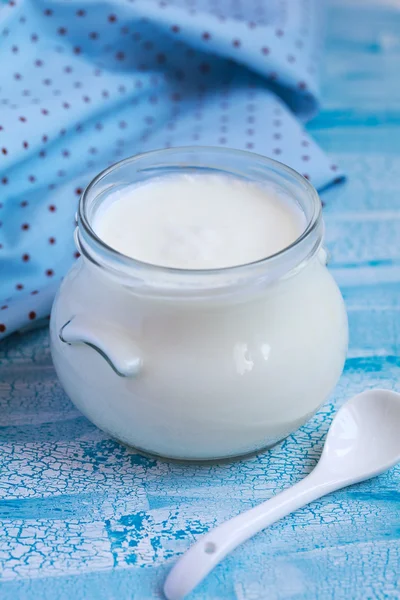 Homemade yogurt in a glass jar on a blue table, selective focus