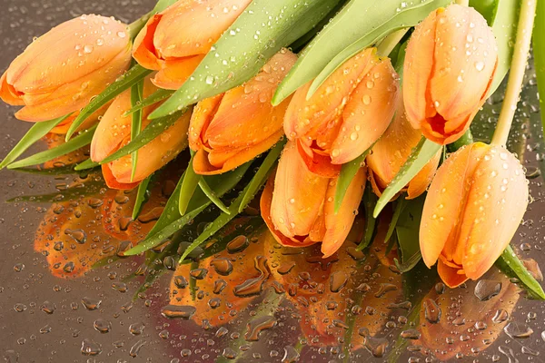 A bouquet of tulips with water drops lying on a silver tray