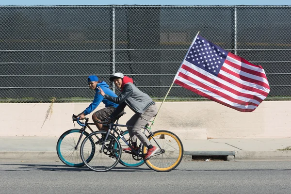Young men riding bicycle holding american flag
