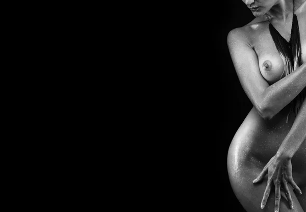 Contours of the female body on a dark background. Sexy body nude woman, naked sensual beautiful girl. Sexy woman lies, darkness, light contours, wet skin. Artistic black and white photo.