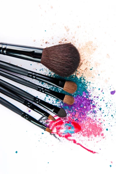 Makeup brushes on white background with colorful powder. Make-up