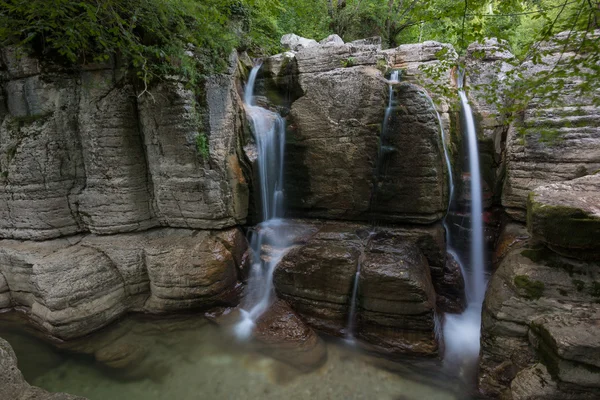 Waterfalls, rocks and lush foliage
