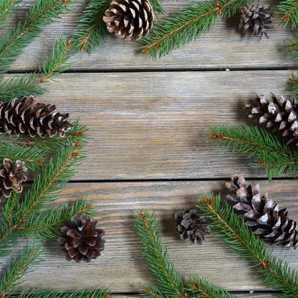 Christmas frame with pine branch and cones on wooden boards