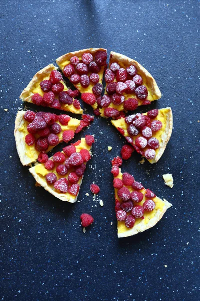Sliced pie with raspberries on slate background