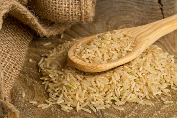 Natural brown uncooked rice on wooden spoon