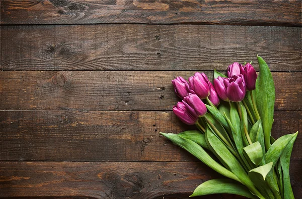 Pink, tulips bunch on dark barn wood planks background. Space for text, copy, lettering. Postcard template.