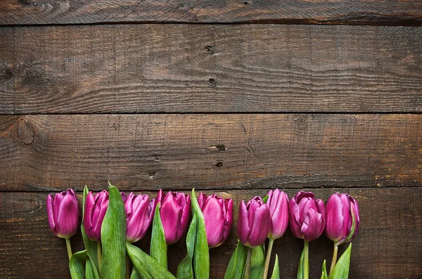 Pink, tulips bunch on dark barn wood planks background. Space for text, copy, lettering. Postcard template.
