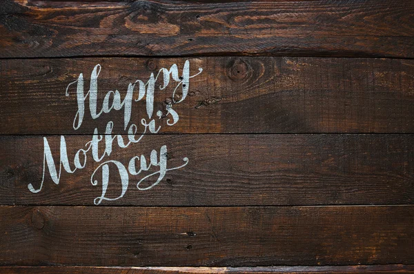 Happy Mother\'s Day lettering calligraphy on dark rustic barn wood holiday background. Space for text, copy, lettering.