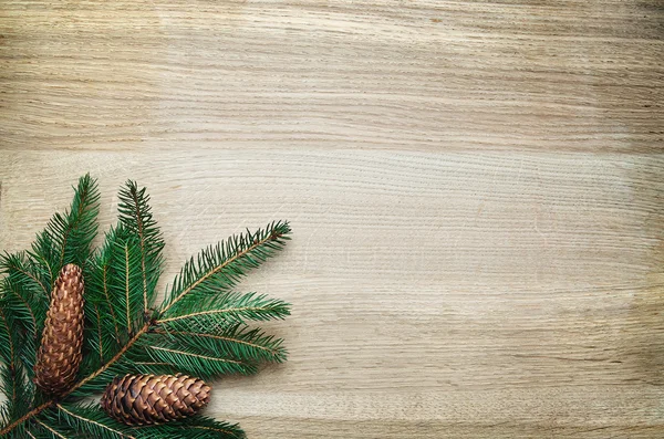 Christmas fir tree twig and pinecones ornament on rustic oak wooden background. Space for lettering