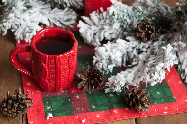 Cup of tea, fir cones, fir branches in the snow, a candle