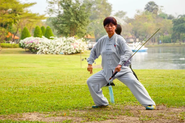 Group of people practice Chinese sword with Tai Chi Chuan in a park