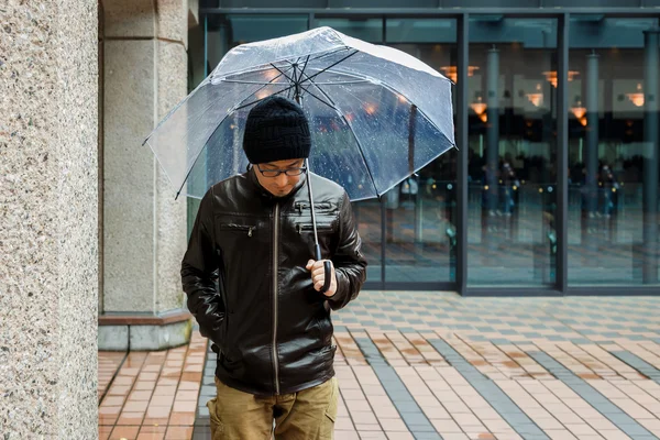 An Asian Man in a Brown Jacket With a Clear Umbrella