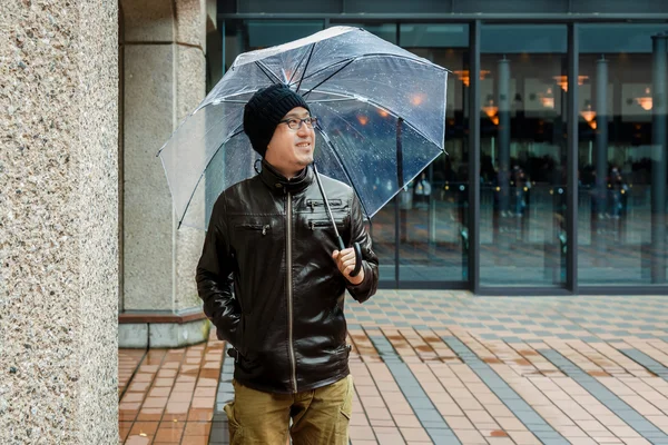 An Asian Man in a Brown Jacket With a Clear Umbrella