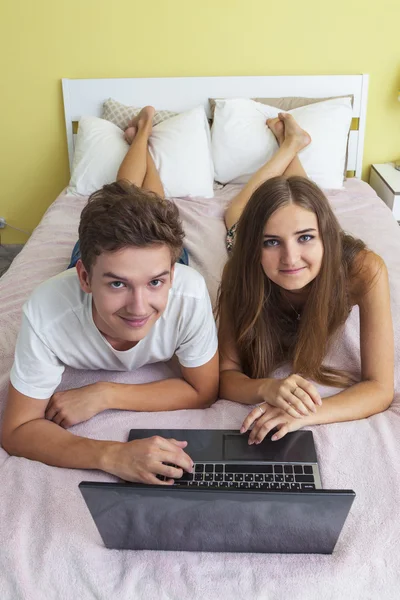 Happy teenager girl and boy watching a laptop