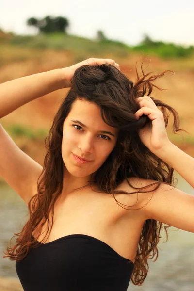 Beautiful slim brunette girl model posing in fashion dress by the sea